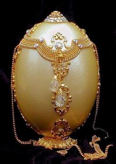 an egg is adorned with gold chains and jewels on it's side, sitting on a black background