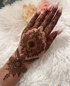 a woman's hand with hennap on it and flowers in the background