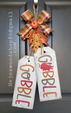 two door hangers decorated with fall leaves and an orange plaid bow are hanging on the front door