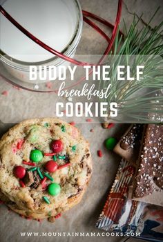 a chocolate chip cookie with candy and sprinkles next to a glass of milk