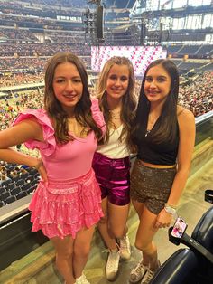 three girls are posing for the camera at a sporting event