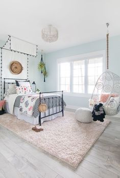 a bedroom with light blue walls and white bedding has a hammock chair in the corner