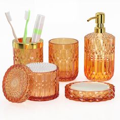 an orange bathroom set with toothbrushes, soap dispenser and cup