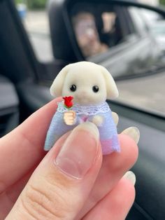 a person holding a tiny stuffed animal in their hand with a flower on it's finger