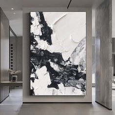 a large black and white painting hanging on the side of a wall in a living room