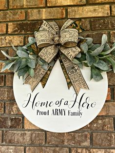 a wreath with the words home of a hero and a bow on it is hanging on a brick wall