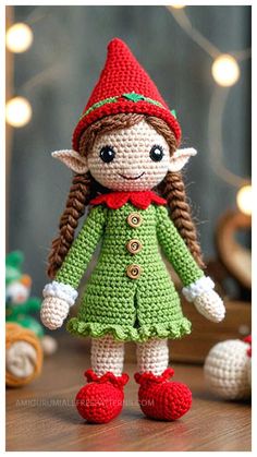 a crocheted elf doll is standing on a table with christmas lights in the background