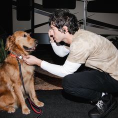 a man kneeling down petting a brown dog