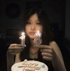 a woman is holding two candles in front of her birthday cake with the number eight on it