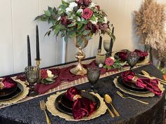 the table is set with black and gold place settings, red napkins, and silverware