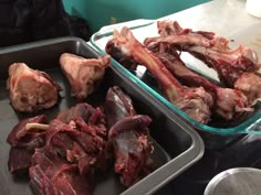 two trays filled with raw meat sitting on top of a counter next to each other