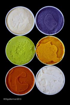 six different colored powders in white bowls on a black background with the letter s