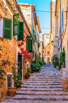 an alleyway with stone steps and green shutters