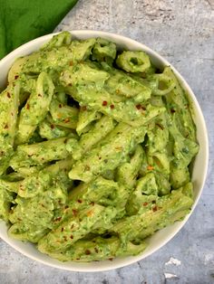 a white bowl filled with green guacamole on top of a table next to a napkin