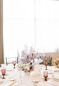 the table is set with place settings and flowers in vases on top of it