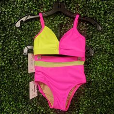 a pink and yellow bathing suit hanging on a green wall