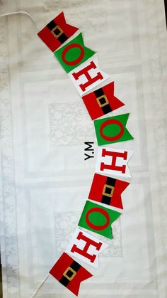 a christmas banner hanging from the side of a white table cloth with red and green letters on it