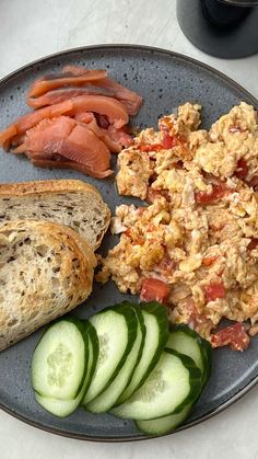 a plate with eggs, cucumbers and bread on it