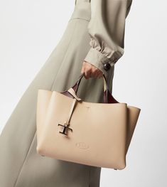 Bag in soft exposed grain leather, with Tod's logo stamped on the front, flat handles and removable shoulder strap. The interior comes with three compartments separated by zipped central pockets. An elegant creation enhanced by distinctive iconic detailing, such as the metal T Timeless pendant and T-stitching. Luxury Beige Pebbled Leather Shoulder Bag, Timeless Bag With Soft Leather And Double Handle, Beige Calf Leather Bag With Top Carry Handle, Beige Calf Leather Bag, Timeless Soft Leather Bag With Double Handle, Timeless Beige Calf Leather Bag, Designer Cream Business Bags, Timeless Beige Soft Leather Bag, Cream Rectangular Calf Leather Bag