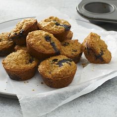 blueberry muffins are on a plate next to a cupcake tin and some paper towels