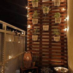 an outdoor patio with potted plants on the wall and lights hanging from the ceiling