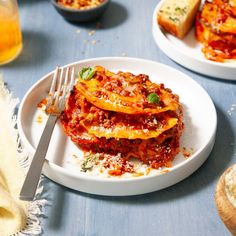 two plates with lasagna and bread on them