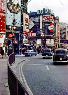 cars driving down the road in front of stores and businesses on a busy street corner