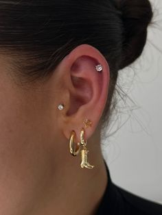 a close up of a person's ear wearing gold earrings with diamond studs