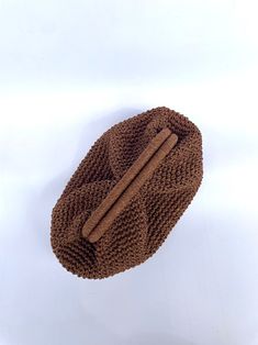 a brown knitted dishcloth with two wooden sticks sticking out of it's center