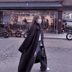 a woman walking down the street wearing a face mask