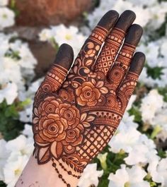 a hand with henna on it and white flowers in the background, all around