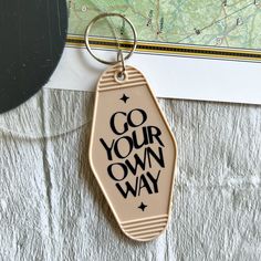 a keychain with the words go your own way written on it next to a map