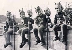 five children dressed up in costumes sitting on top of a wall and holding onto poles