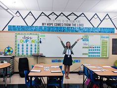 a woman standing in front of a whiteboard with writing on it and her arms up