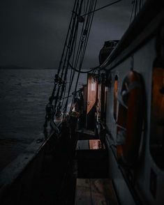 the back end of a boat in the ocean under a dark sky with storm clouds