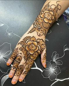 a woman's hand with henna tattoos on her left arm and the top half of