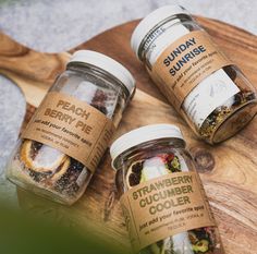 three jars filled with different types of food on top of a wooden cutting board next to each other