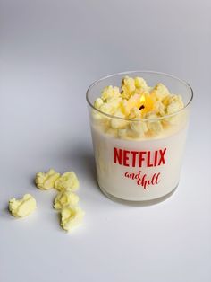 a glass bowl filled with popcorn sitting on top of a white table next to pieces of butter