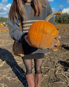 a woman in tights and boots holding a pumpkin with her head turned to the side