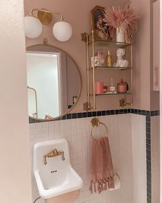 a white toilet sitting next to a sink in a bathroom under a mirror and shelf