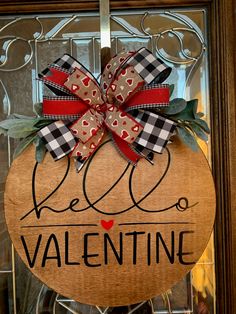 a wooden sign that says valentine's day hanging on a glass door with a bow