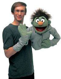 the man is posing with his hand puppet