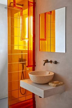 a bathroom sink sitting under a mirror next to a walk in shower and tiled walls