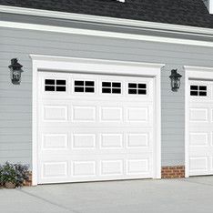 three white garage doors in front of a gray house