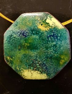 a green and yellow pendant on a black surface