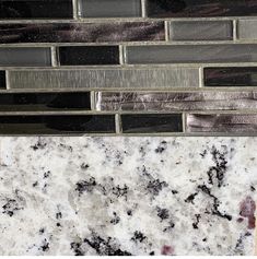 a close up view of some black and white marble tiles on a wall with silver trim