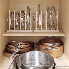 pots and pans are lined up on shelves in a cupboard with utensils