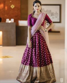 a woman in a purple and gold lehenga standing with her hands on her hips