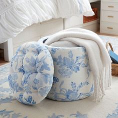 a blue and white flowered pouff on a rug in a bedroom with a bed