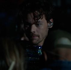 a close up of a person in a dark room with other people looking at something